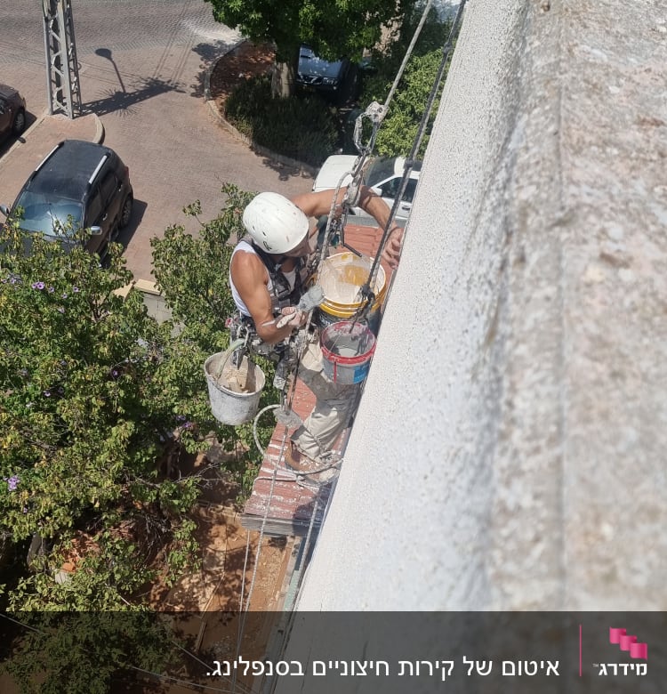 אדם על חבל אוטם קיר עם מברשת ודלי